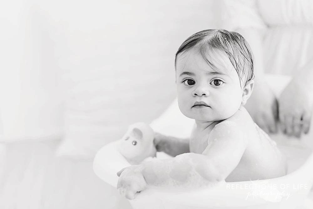 little girl plays with rubber duck in black and white in natural light studio