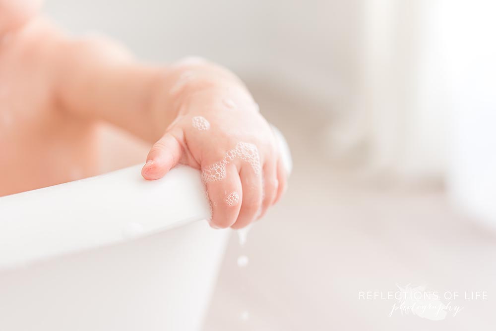 little girl holds onto the side of the tub in natural light studio