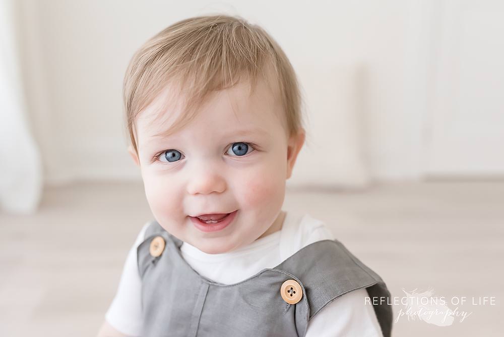 little boy smiles at the camera in natural light studio