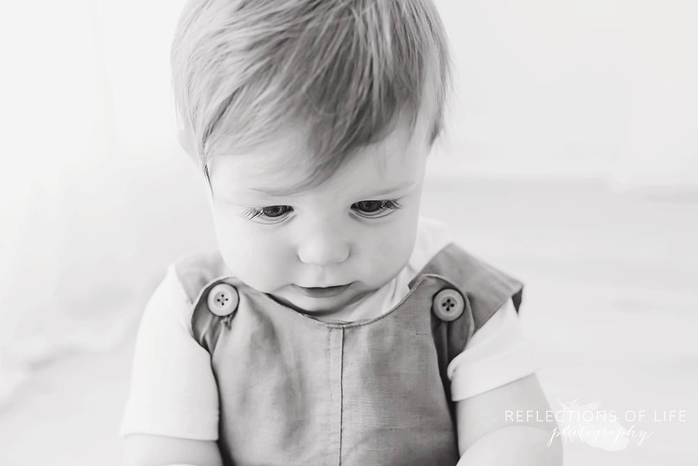 little boy looks at the ground in black and white
