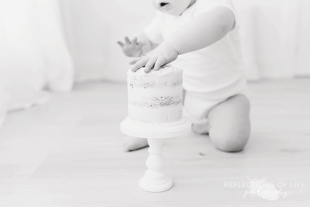 close up of baby's hand on a cake in black and white
