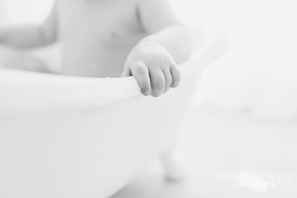 close up of baby's hand gripped onto the side of the tub in black and white