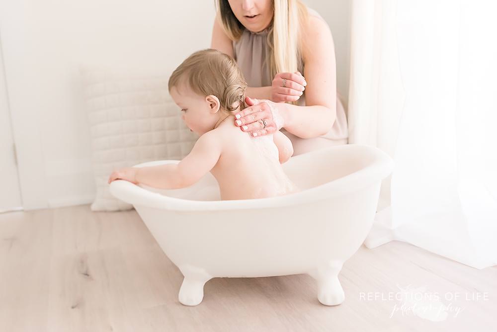 mama rubs water on his back in the tub