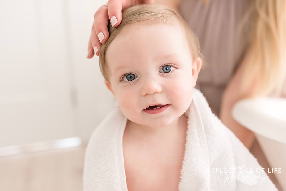 beautiful boy smiles at the camera as his mama rubs his head