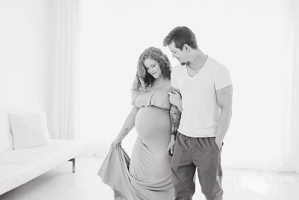 couple walks around a natural light studio as she lifts her dress up in black and white