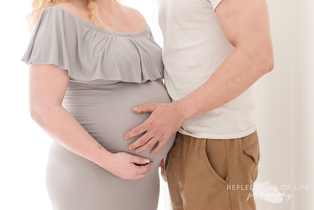 father of baby puts his hand on expecting mamas belly
