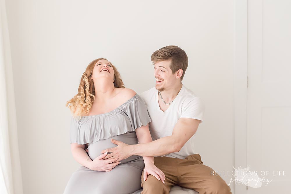 father of baby makes mama laugh in natural light studio