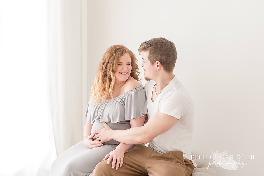expecting mama giggles as her husband holds her belly