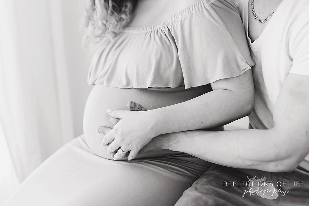 expecting parents hold their belly in black and white