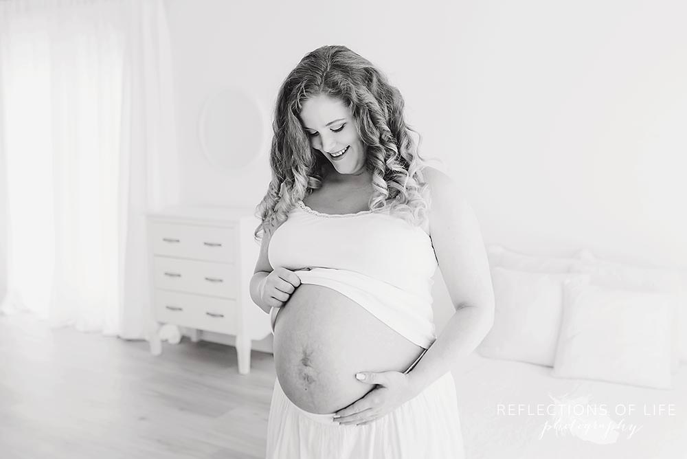 mama smiles at her baby bump in black and white
