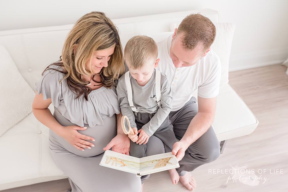 Expecting family reads a book together on the couch Niagara maternity photos