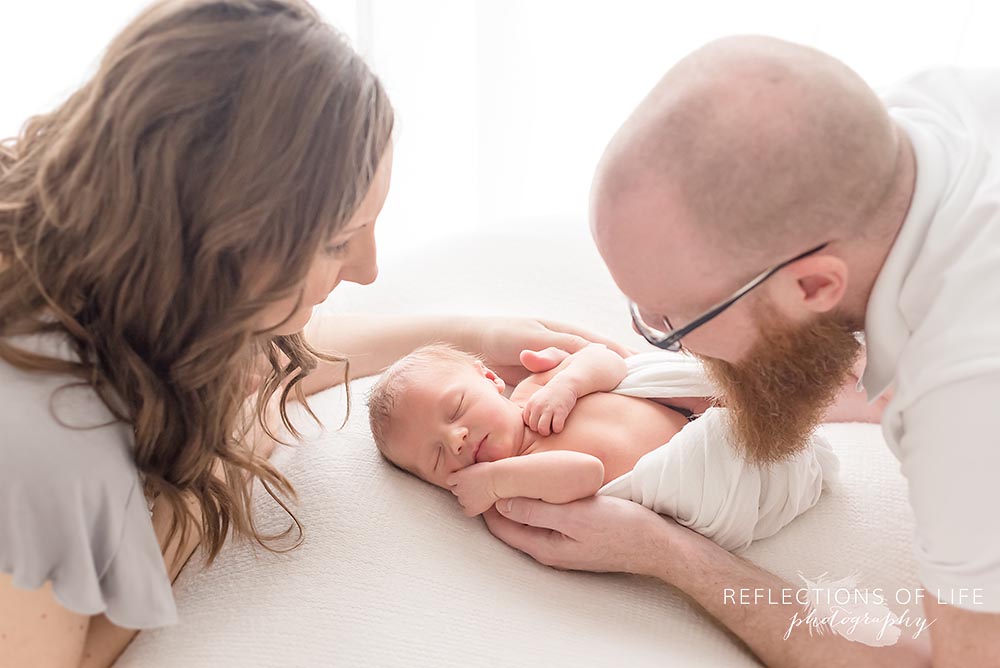 Mom and dad look down at beautiful baby boy they made