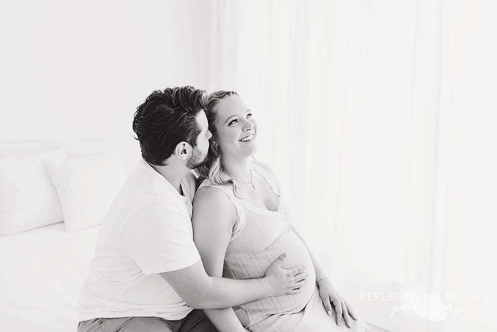 pregnant couple laughing in black and white