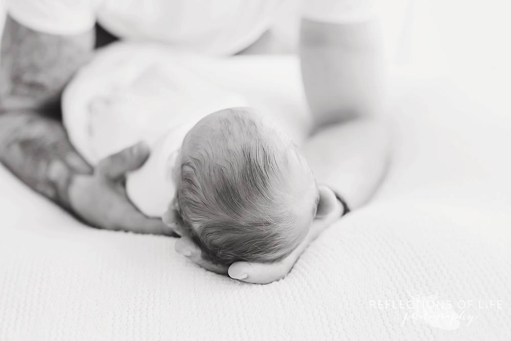 Newborn baby head in his daddy's hands