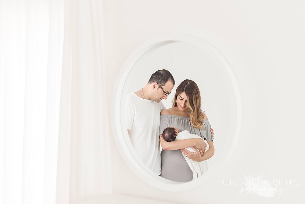 New parents cuddle new baby in mirror.jpg