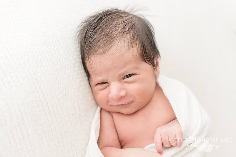 Adorable newborn baby boy smiling at the camera.jpg