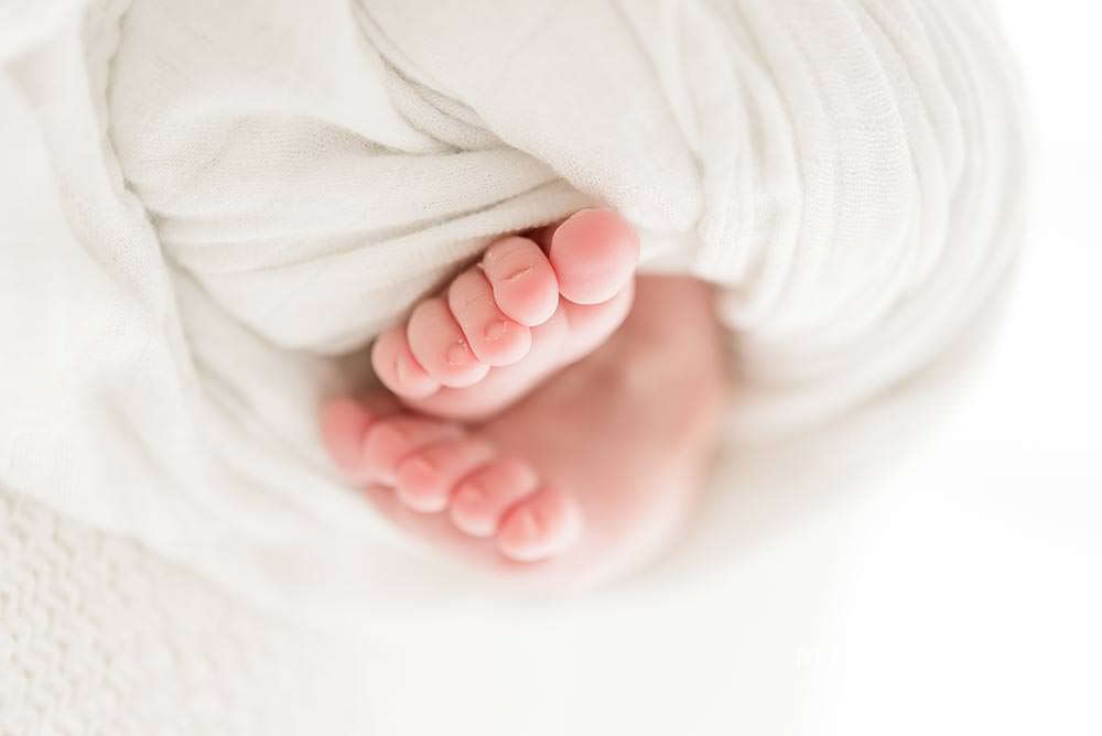 Newborn baby boy feet wrapped in white little unicorn blanket.jpg