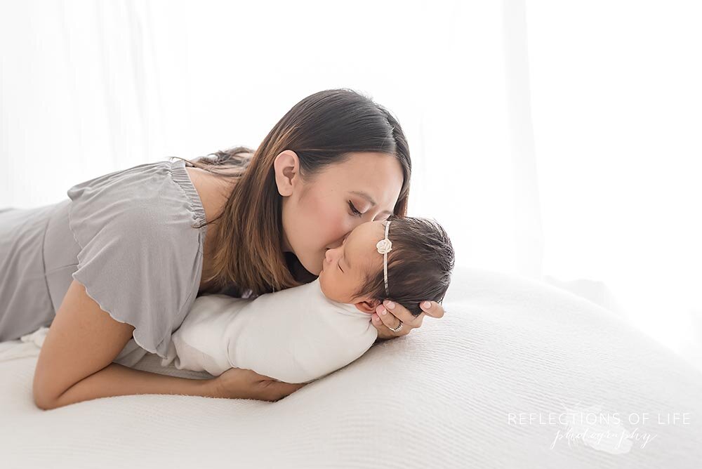 Mother and newborn daughter snuggling in white studio.jpg