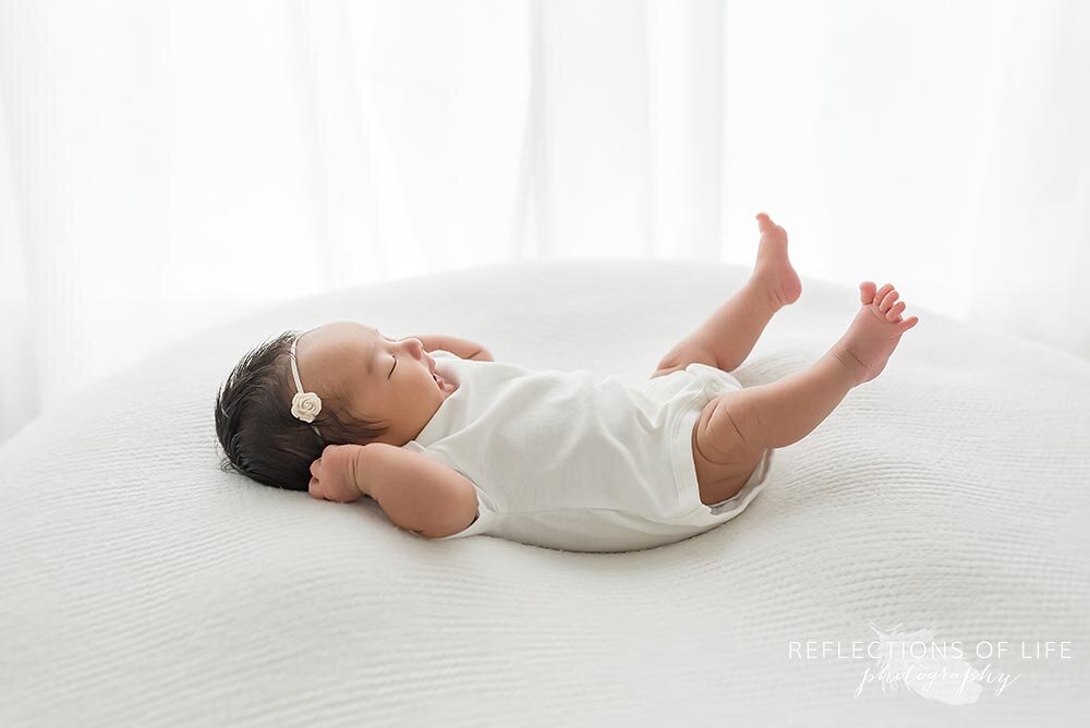 Newborn baby girl stretches out her legs in Hamilton Ontario natural light studio.jpg