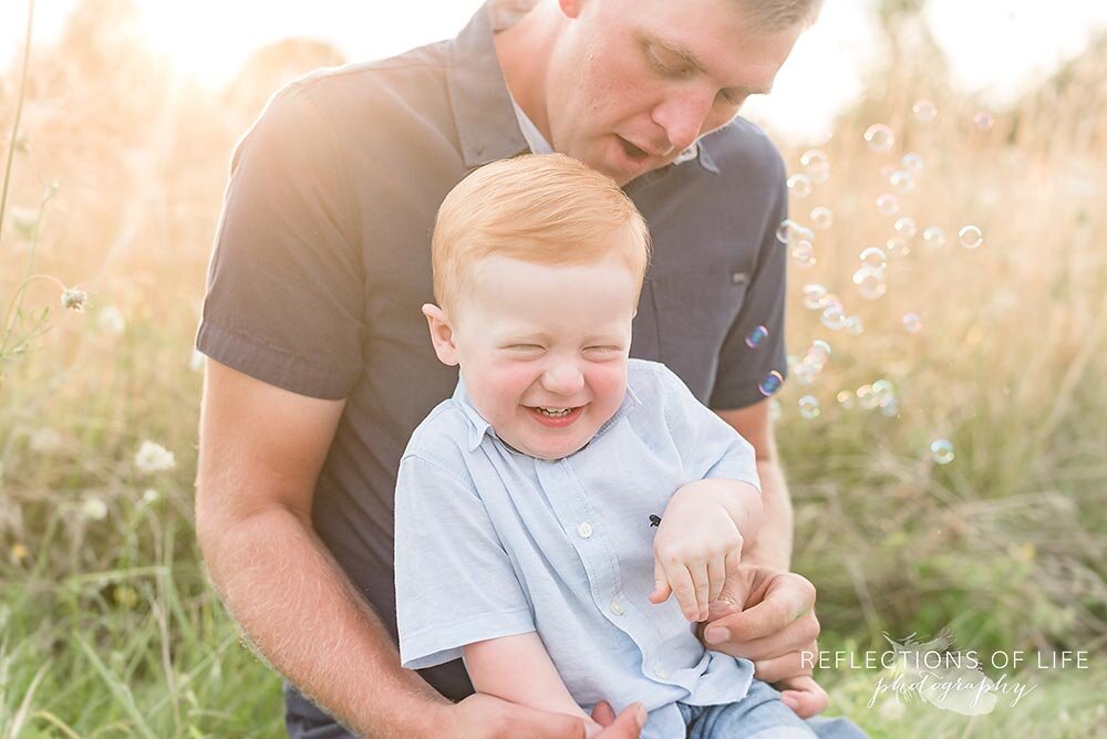 Little ginger boy laughing on his dads lap