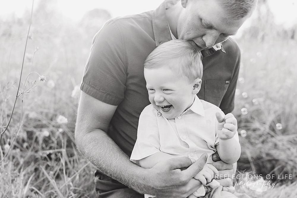 Little boy giggling on his dads lap in black and white