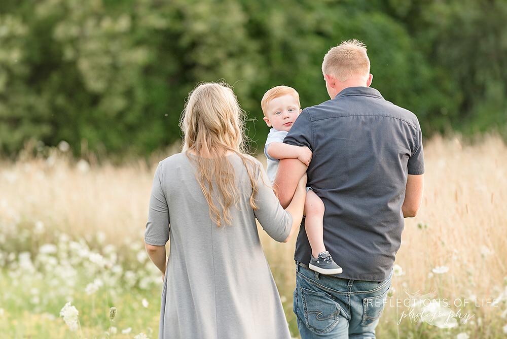 Little boy looks at camera while his parents walk away