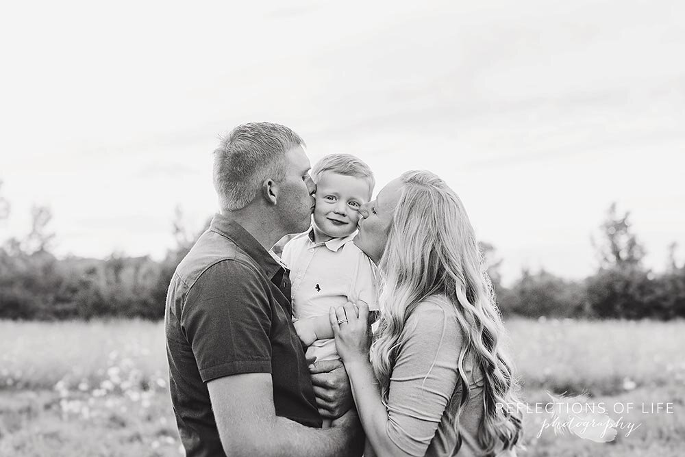 Cure photo of parents kissing their son on the cheeks