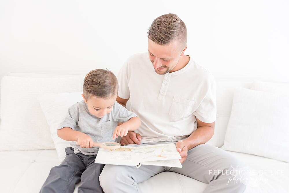 Father and son reading a book with magnifying glass Niagara family photographer.jpg