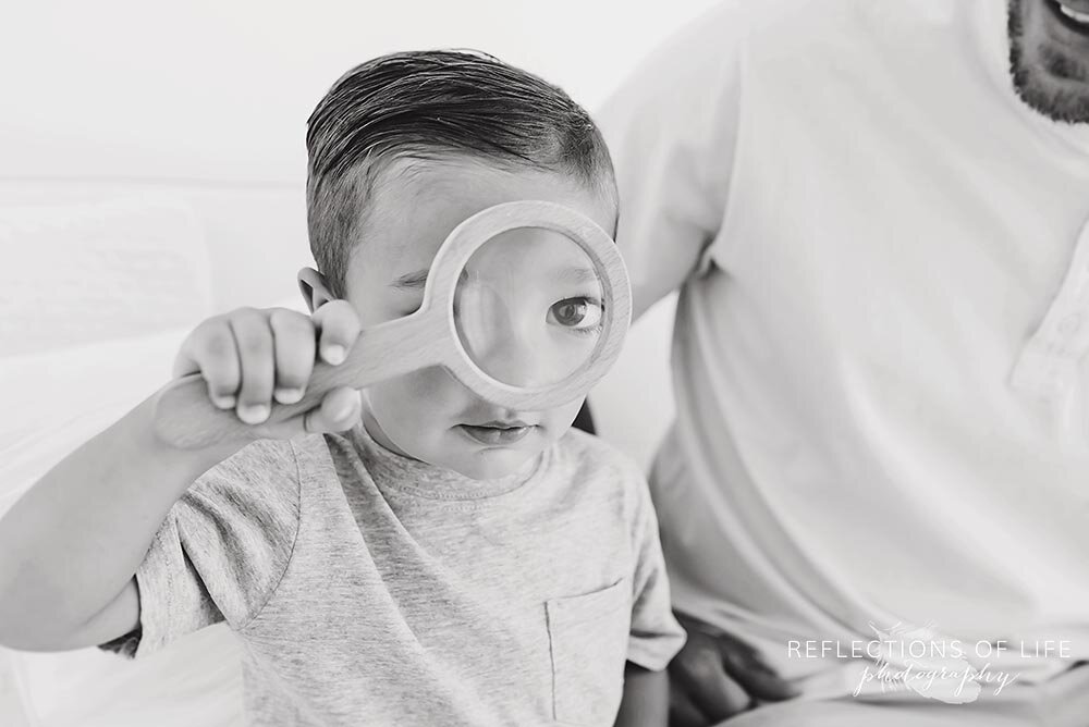 Little boy looks at camera through magnifying glass.jpg