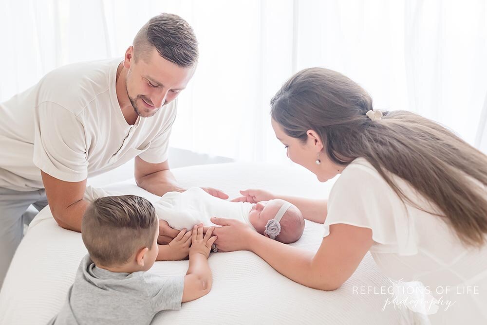 Newborn baby sleeping with her big brothers hands on her Hamilton Newborn Photographer.jpg