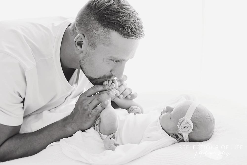 Daddy kisses his newborn baby girls toes Niagara Photographer.jpg