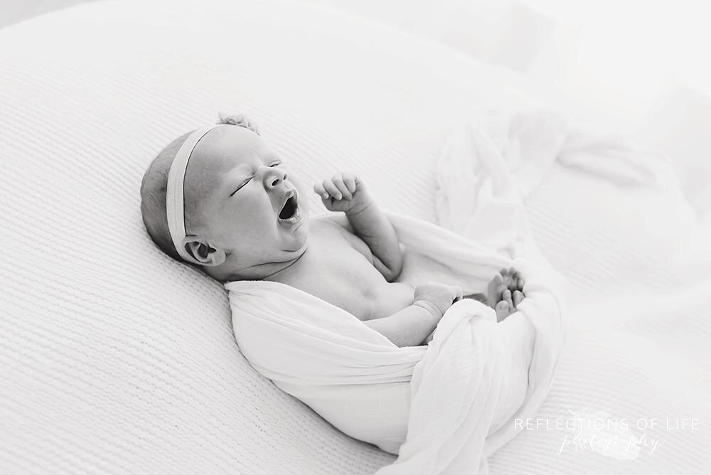 Little newborn baby girl yawns in little unicorn swaddle blanket.jpg