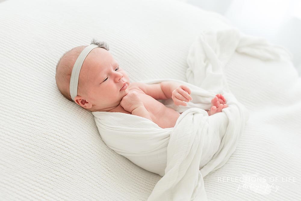 Little baby girl places her hands under her chin Niagara Newborn Photography.jpg