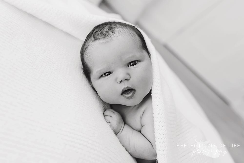 newborn baby girl looks into camera lens