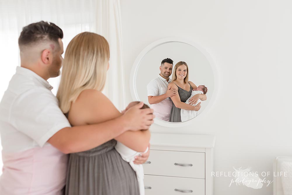 newborn baby girl and parents reflection in mirror