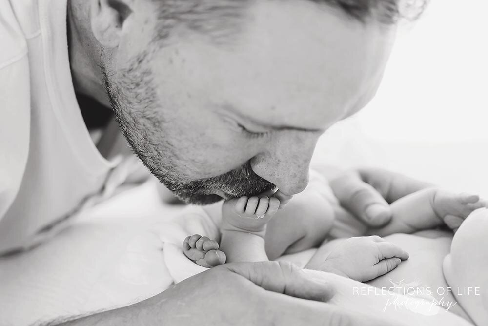 Daddy kissing newborn baby toes