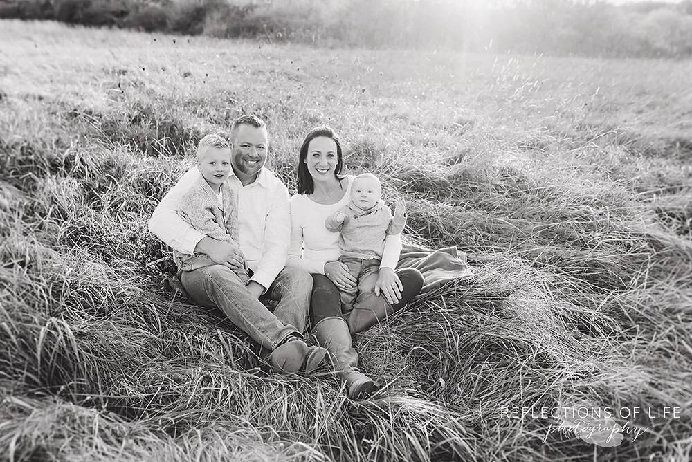 Black and white image of family in a sunset covered field.jpg