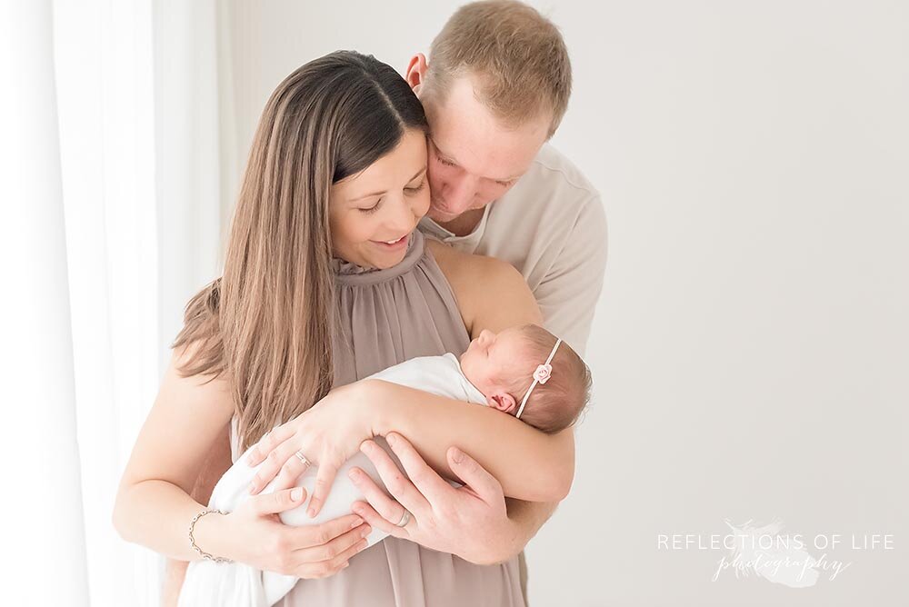 Newborn baby girl being held by her loving parents Hamilton Newborn Photographer