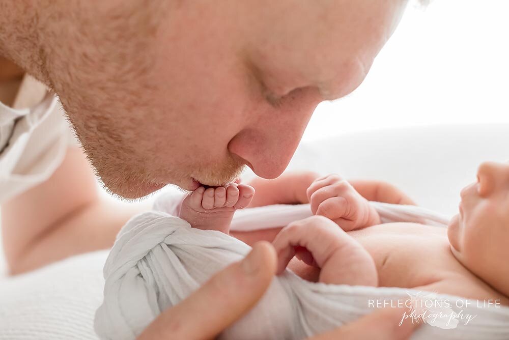 New daddy kisses newborn baby girl toes