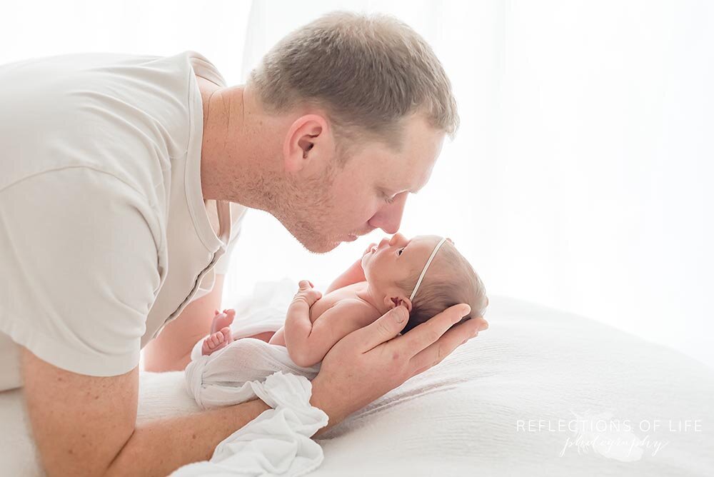 daddy rubs noses with newborn baby girl