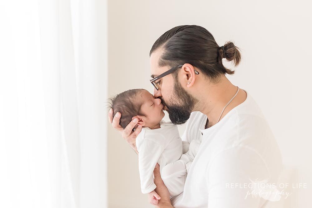Daddy kissing his newborn sons face Grimsby Ontaroi photo studio