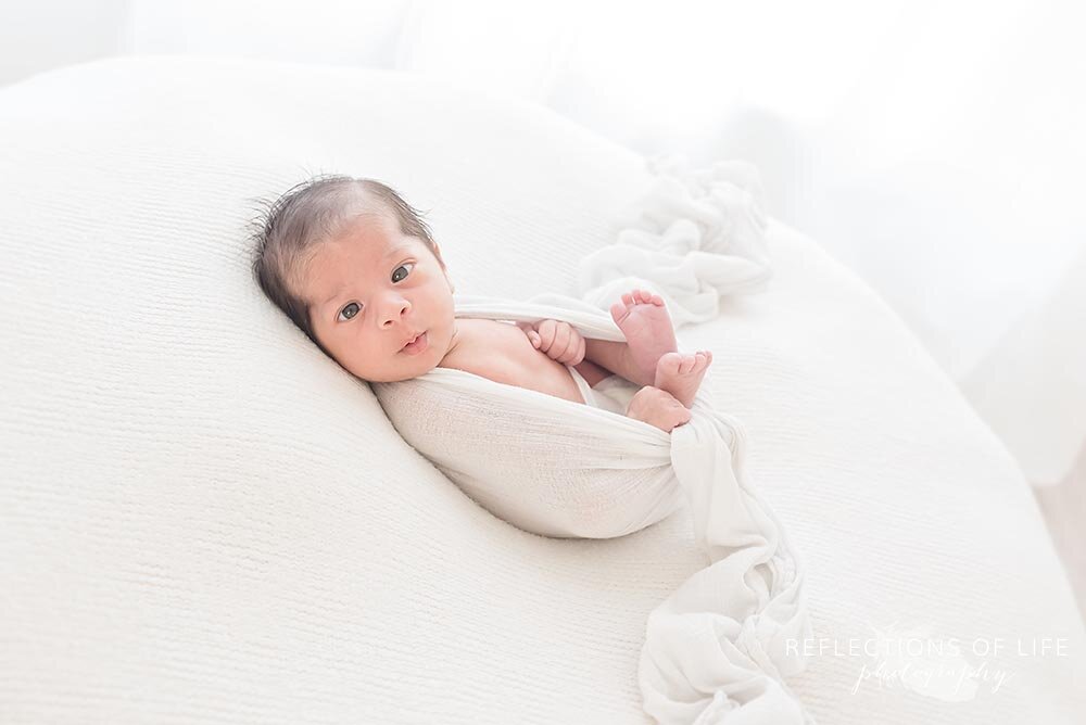 Baby boy wrapped in white swaddle blanket
