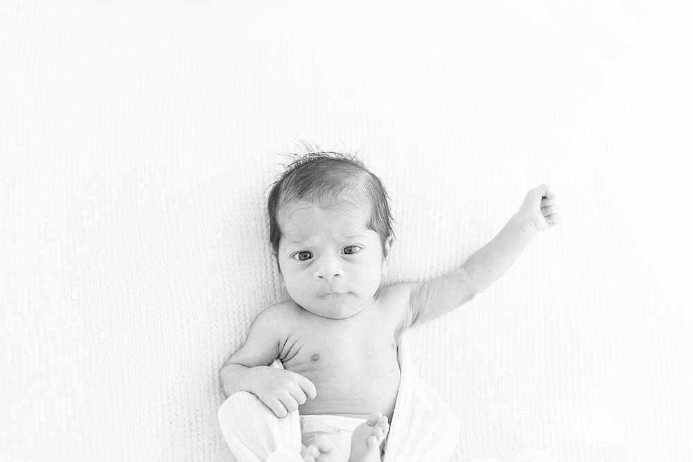 Newborn baby boy with his arm up in the air in black and white Hamilton photoshoot