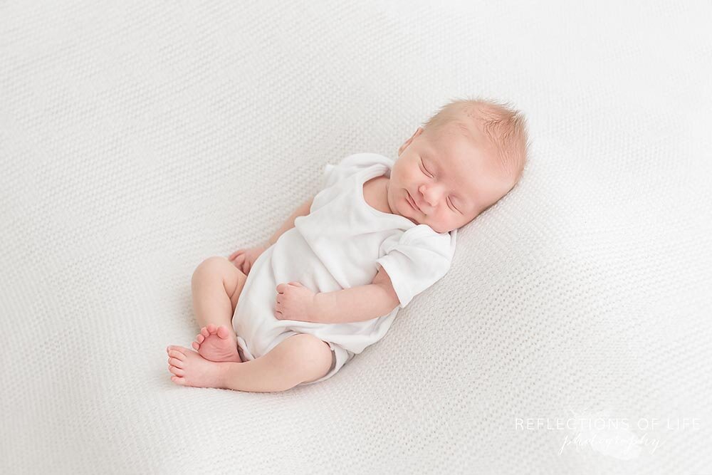 Cute newborn baby boy dressed in white onesie Niagara Falls Ontario Canada