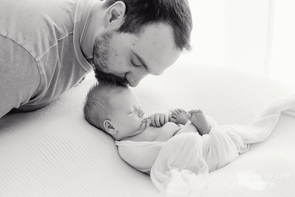 Daddy kisses his baby's head in black and white