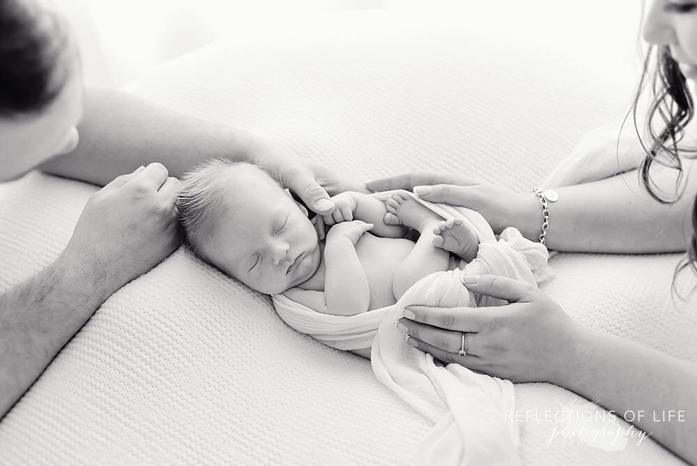 Newborn baby boy with his parents arms on and around him Grimsby Ontario Canada