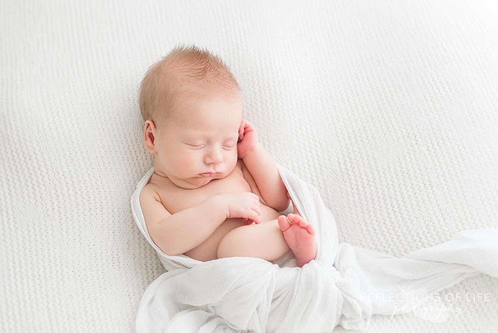 Newborn baby boy wrapped in white swaddle Niagara Ontario portrait studio