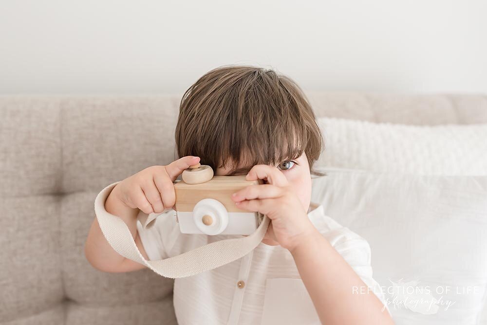 Little boy looking through wooden camera lens Grimsby Ontario photography studio