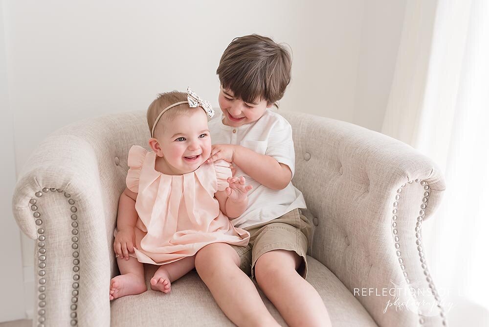 Sibling tickling each other on the chair Neutral family photography