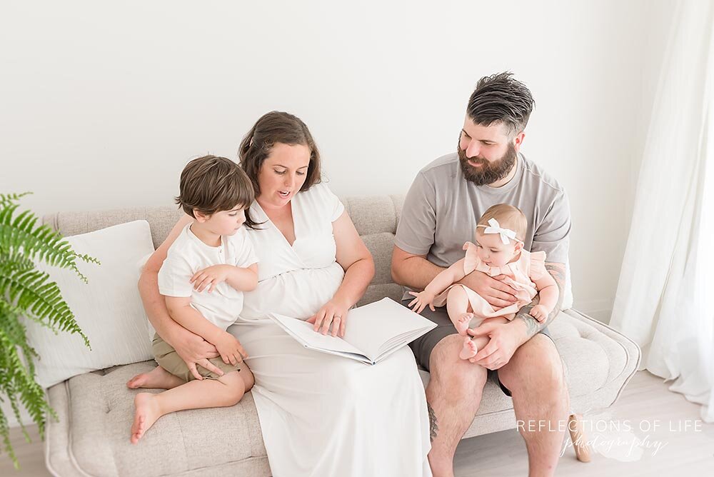 Family reading a story together on the couch in white studio Grimsby Ontario Photo Studio